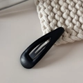 Vue détaillée d'une pince à cheveux noire en cuir sur fond en maille beige - Goutte d'Eau en Cuir Creux BB-Noir