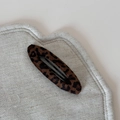 Primo piano della molletta con stampa leopardata su sfondo di tessuto beige - Clip BB Ovale Leopardato