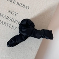 Detail einer großen Haarklammer mit elegantem, schwarzem, gefaltetem Satingewebe - Schwarz