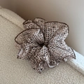 Detail van een holle mesh geweven scrunchie in beige en zwart met bruine rand - Beige