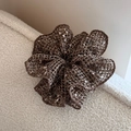 Gedetailleerde macro van een donkerbruine gebreide scrunchie met witte textuur - Bruin