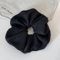 Detalle de coletero de punto negro con textura de panal y etiqueta de marca tejida - Negro