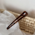 Detailed close-up of a dark leopard print tortoise shell resin hair pin on a woven basket - Dark Leopard Hollow Straight