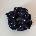 Detail van zwarte stoffen scrunchie met wit hartjespatroon en zachte geplooide textuur - Marine Denim Hartpatroon