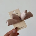 Detail of champagne satin bow hair clip on premium white textured display card - Apricot