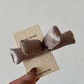 Dettaglio di un fermaglio per capelli a fiocco in raso marrone champagne su una card - Champagne
