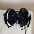 Detailed close-up of large black layered organza bow with white lace edges and gold charm - Chiffon Ponytail Clip / Black