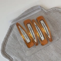 Detail of amber resin hair clips set with silver metal base on grey linen background - Set of 4 / Triangle Coffee (FJ892956)