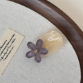 Dettaglio ravvicinato di un fermaglio per capelli in resina con eleganti petali viola - Fiore Viola Grigio - Base Beige