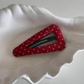 Detalle de una pinza para el cabello triangular con lunares rojos en plato blanco - Triángulo de Lunares Rojos
