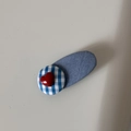 Detailed view of a denim fabric hair clip with a blue checkered button and red heart - Light Denim - Oval Heart