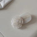 Détail macro d'une pince à cheveux camélia avec pétales en résine et base texture marbre - Blanc Scintillant