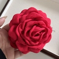 Primo piano di una grande spilla a camelia in tessuto rosso con petali a più strati - Rosso