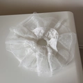 Detail eines weißen Spitzen-Haargummis mit Punkten und elegantem, gestuftem Mesh-Rüschendesign - Reinweiß Spitze - Spitzenkante