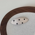 Vue macro d'une pince à cheveux ovale en satin à pois noirs sur tissu crème avec coutures - Beige Black Dot