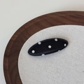 Vue détaillée de la barrette ovale en satin noir à pois sur un support en lin et bois - Noir à Pois Blancs