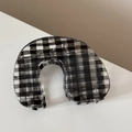 Gros plan sur une pince à cheveux à motif damier noir et blanc au fini brillant - Style en Forme de U