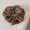 Close-up of brown gold mesh textured scrunchie with high elastic band and woven label - Brown
