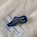 Vue rapprochée d'une pince à cheveux ondulée bleu marine sur un tissu blanc texturé - Style Torsadé Bleu Marine