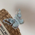 Macro detail of a colorful marble butterfly clip with SAN engraving on woven fabric - Cyan