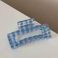 Dettaglio macro di un fermaglio per capelli a quadretti azzurro con molla dorata - Quadri Traslucidi - Rettangolo Blu Chiaro