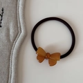 Gros plan d'un nœud en résine ambrée sur un élastique à cheveux noir haute élasticité - Cravate à cheveux / Marron
