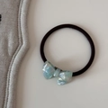 Gros plan sur un élastique à cheveux noir avec un pendentif nœud bleu clair nacré - Cravate à cheveux / Vert/Blanc