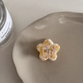 Détail de la mini pince à cheveux fleurie en acétate marbré avec cristal dans un plat en céramique - Jaune/Blanc