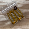Detailed view of four mustard yellow BB hair clips in professional transparent packaging - Yellow