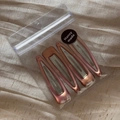 Detailed view of four rose gold metallic BB hair clips in clear packaging with a brand label - Pink
