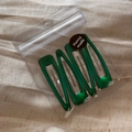 Set of four shiny green triangular hair clips in transparent bag with a black seal sticker - Green