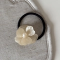 Detailed macro of a cream acetate flower hair clip with a centered glossy pearl bead - Rhinestone Pearl Flower (FJ891537) / Beige Hair Tie