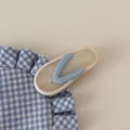 Nahaufnahme der Haarspange in Flip-Flop-Form mit blauen Riemen auf kariertem Stoff - Cremeweiß