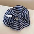 Detalle de un scrunchie de tela a rayas azules y blancas con etiqueta tejida - Rayas Azul Marino - Coletero