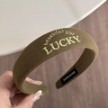 Macro detail of Lucky embroidery on olive green sponge headband with handmade label - Brown