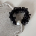 Detail view of a black pleated mesh hair scrunchie with a large white pearl embellishment - Black