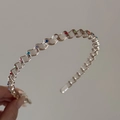 Detail view of transparent wavy headband with multi-colored crystals for hair styling - Brown