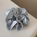 Macro detail of elegant silver-grey satin scrunchie with glossy ruffled fabric texture - Blue