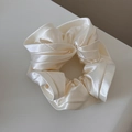 Detailed view of the pearlescent ivory satin scrunchie with elegant ruffled texture - Off White