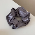 Detail of grey satin scrunchie with a glossy silk texture and elegant ruffled design - Gray