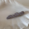 Détail d'une pince à cheveux en tissu à carreaux bleus et beiges sur un plateau blanc - Forme vague / Carreaux Bleu Clair