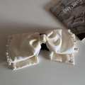 Detail shot of a beige satin bow hair claw clip with delicate pearl trim on smooth surface - Pearl Bow Half Claw-Beige