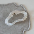 Dettaglio di un elegante fermaglio per capelli in acetato bianco con bordo a onda dorato - Forma di Nuvola (FJ891491)