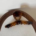 Close-up of elegant amber brown translucent hair claw clip on wooden tray and linen - Glossy Tortoiseshell