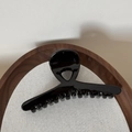 Close-up of a glossy black hair claw clip resting in a wooden tray with fabric lining - Glossy Black