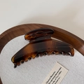 Detailed macro view of a large amber tortoiseshell hair claw clip with a strong metal spring - Tortoiseshell
