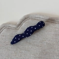 Detail of navy blue polka dot fabric hair clip on a beige textured linen display pad - Navy Blue Polka Dot Wave Duck Clip