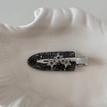 Dettaglio di un fermaglio per capelli a stella in acetato nero con strass scintillanti - Stile Brillante / Nero Luccicante