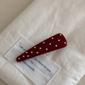 Gros plan d'une pince à cheveux triangle bordeaux à pois sur tissu en lin blanc - Grand Triangle (7cm)