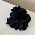 Detailopname van de glanzende zwarte satijnen bloembladen van deze haaraccessoire - Zwart
